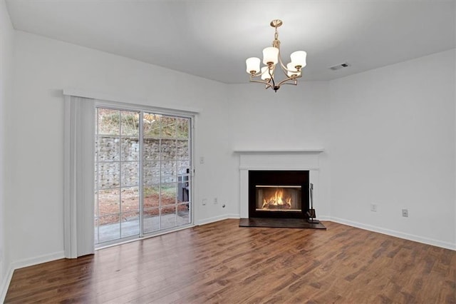 unfurnished living room featuring visible vents, baseboards, a chandelier, wood finished floors, and a glass covered fireplace