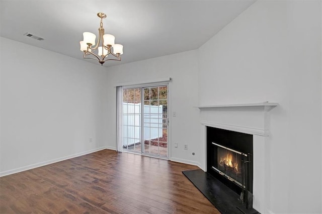 unfurnished living room featuring visible vents, a glass covered fireplace, dark wood finished floors, an inviting chandelier, and baseboards