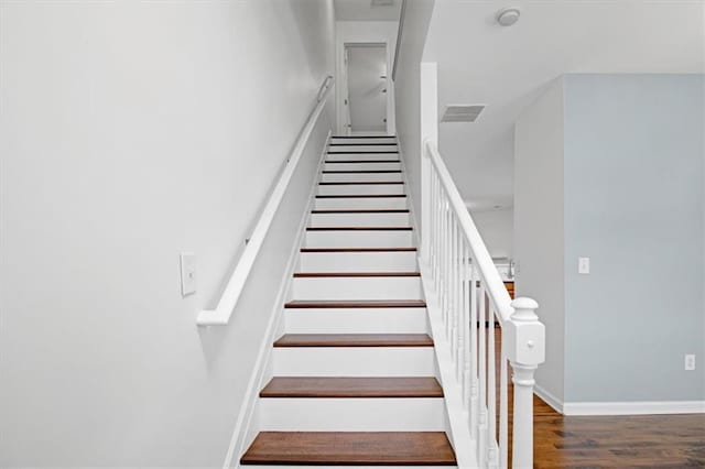 stairs with visible vents, baseboards, and wood finished floors