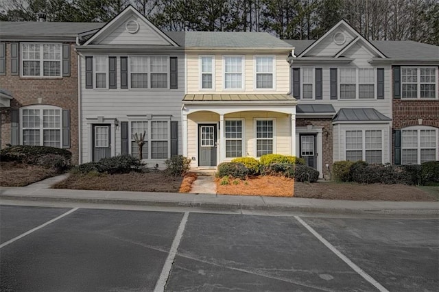 view of property with a standing seam roof and uncovered parking