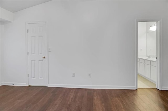 spare room featuring a sink, baseboards, and wood finished floors