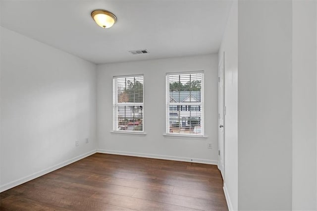 spare room featuring dark wood-type flooring, baseboards, and visible vents