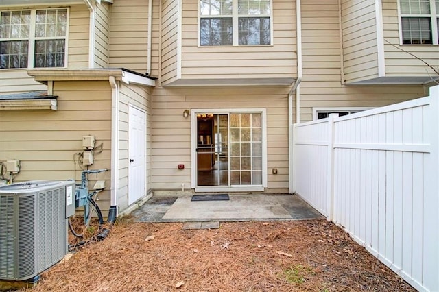 doorway to property with a patio area, cooling unit, and fence