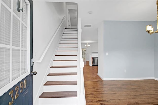 stairs featuring visible vents, baseboards, an inviting chandelier, and wood finished floors