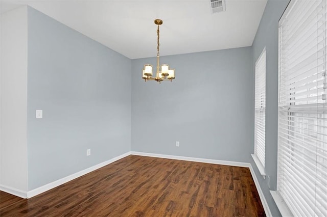 spare room featuring visible vents, a healthy amount of sunlight, baseboards, an inviting chandelier, and dark wood-style floors