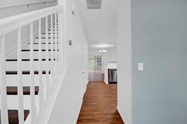 corridor featuring visible vents, dark wood finished floors, an inviting chandelier, baseboards, and stairs