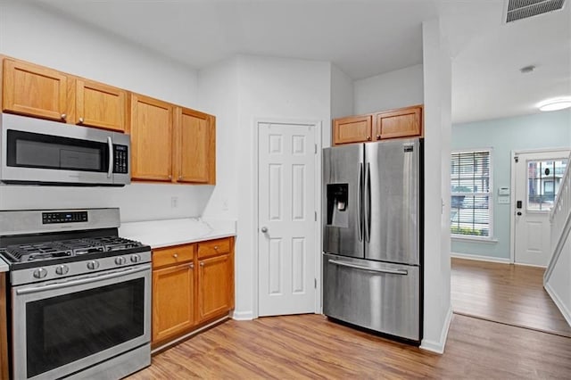 kitchen featuring visible vents, light wood-style flooring, appliances with stainless steel finishes, and baseboards