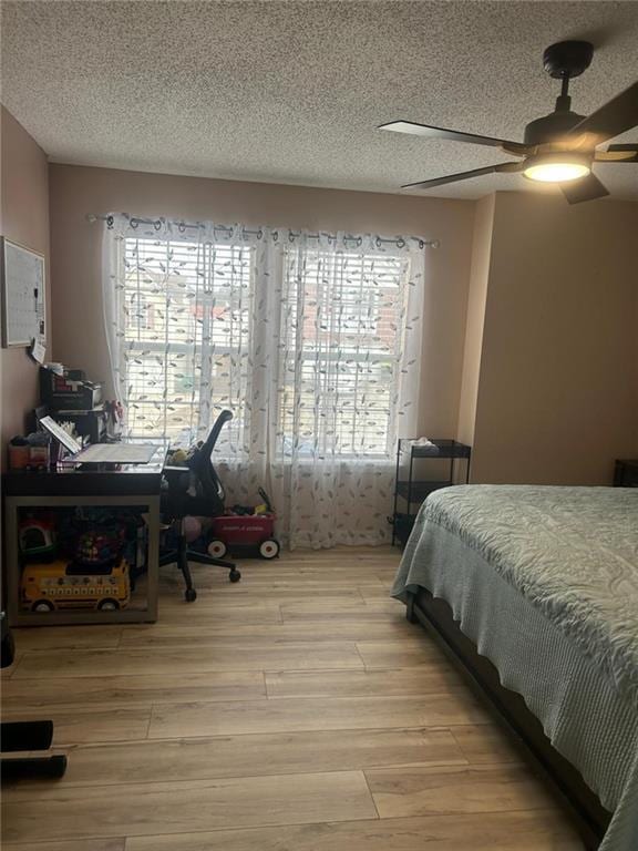 bedroom with ceiling fan, a textured ceiling, and light hardwood / wood-style floors