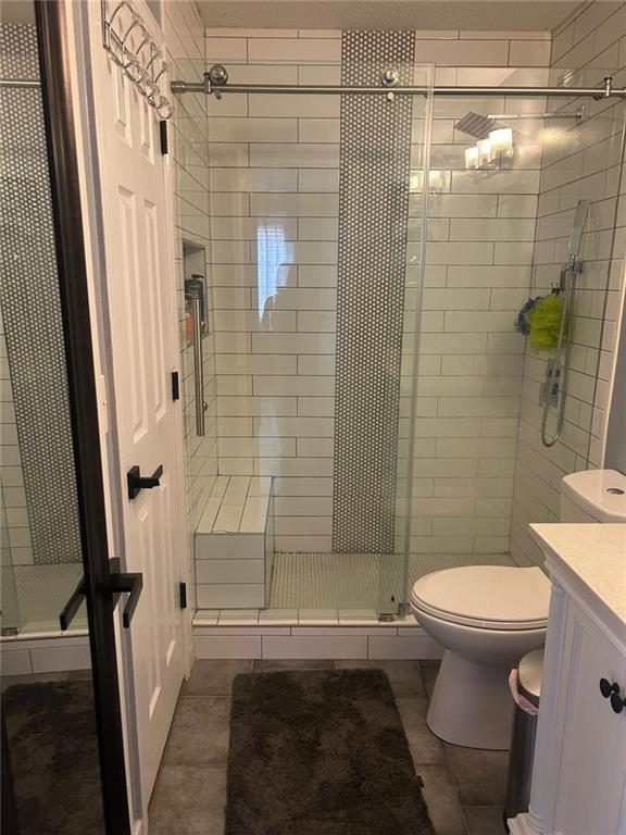 bathroom featuring vanity, an enclosed shower, tile patterned floors, and toilet