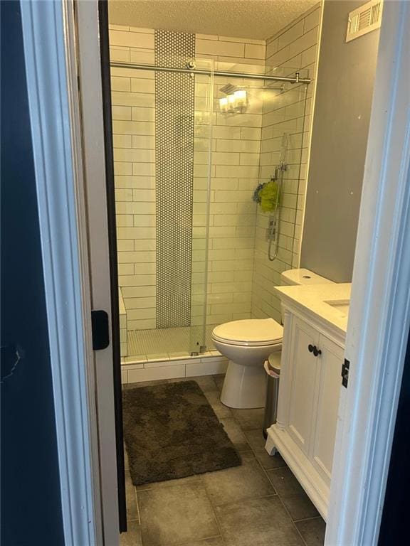 bathroom with vanity, toilet, a shower with door, tile patterned floors, and a textured ceiling