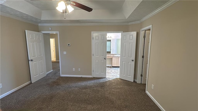 unfurnished bedroom with ceiling fan, dark carpet, crown molding, and a raised ceiling