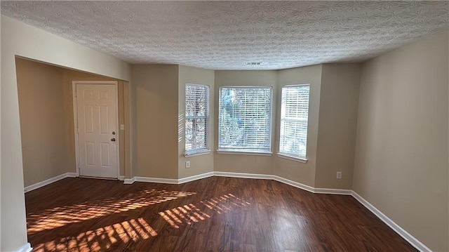 empty room featuring dark hardwood / wood-style flooring and a textured ceiling