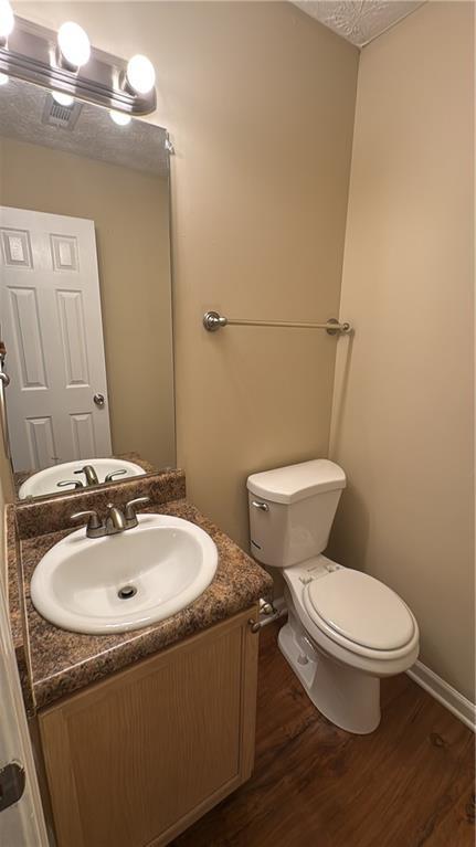 bathroom with a textured ceiling, toilet, hardwood / wood-style floors, and vanity