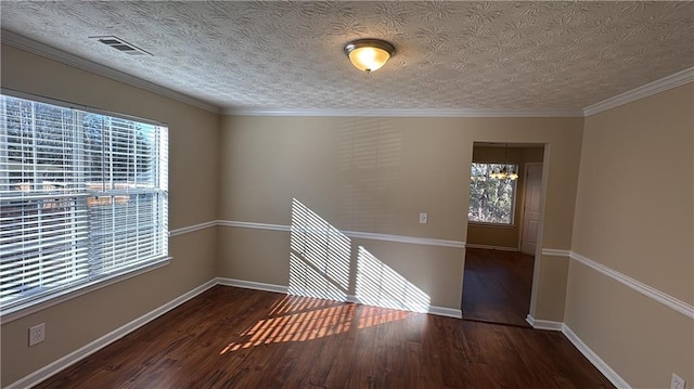 empty room with a textured ceiling, dark wood-type flooring, ornamental molding, and a notable chandelier