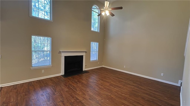 unfurnished living room with ceiling fan, dark hardwood / wood-style floors, and a towering ceiling