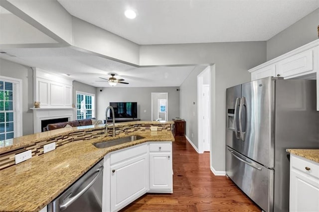 kitchen with a ceiling fan, open floor plan, dark wood-type flooring, a sink, and stainless steel appliances