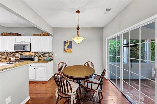 dining room featuring dark wood-style flooring and a textured ceiling