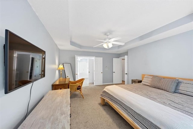 carpeted bedroom featuring baseboards, ceiling fan, and a tray ceiling