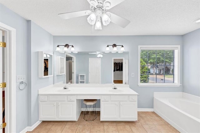 bathroom featuring a sink, double vanity, a textured ceiling, a ceiling fan, and a garden tub