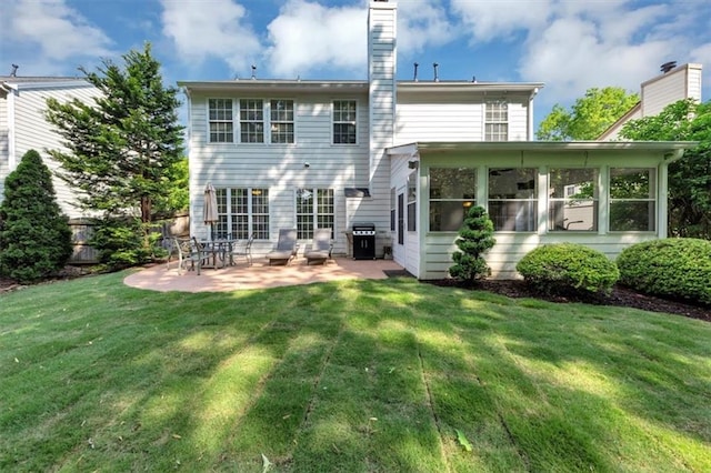 back of house featuring a yard, a patio, a chimney, and a sunroom
