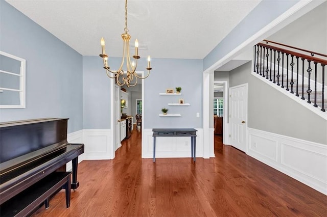 dining space with an inviting chandelier, stairs, wainscoting, and wood finished floors