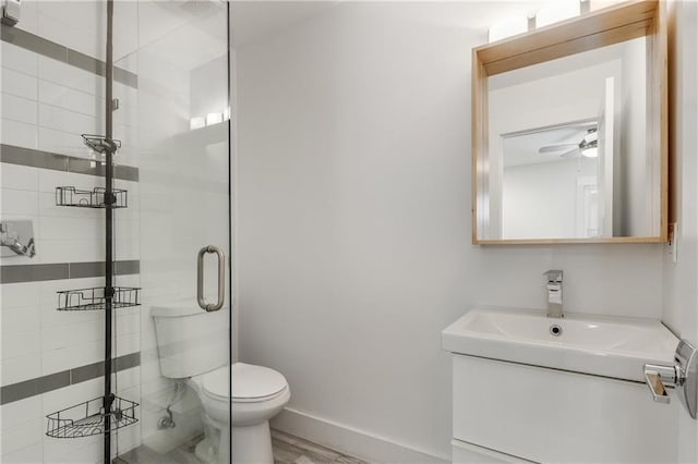 full bath with toilet, a stall shower, vanity, a ceiling fan, and baseboards