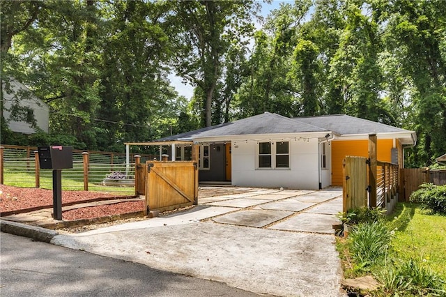ranch-style house featuring concrete driveway, a gate, roof with shingles, and fence
