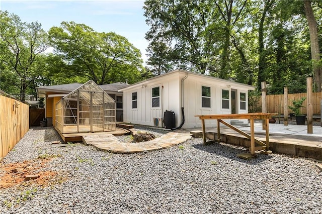 back of house with board and batten siding, a fenced backyard, a patio, and an outdoor structure