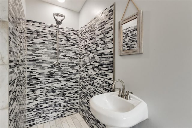 full bathroom featuring a tile shower and a sink