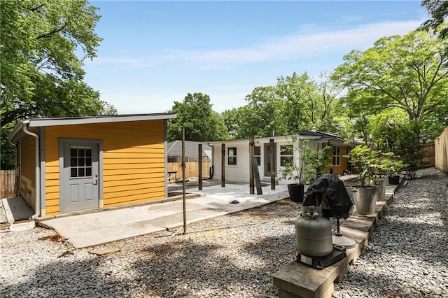back of property featuring a fenced backyard, a patio, and an outbuilding