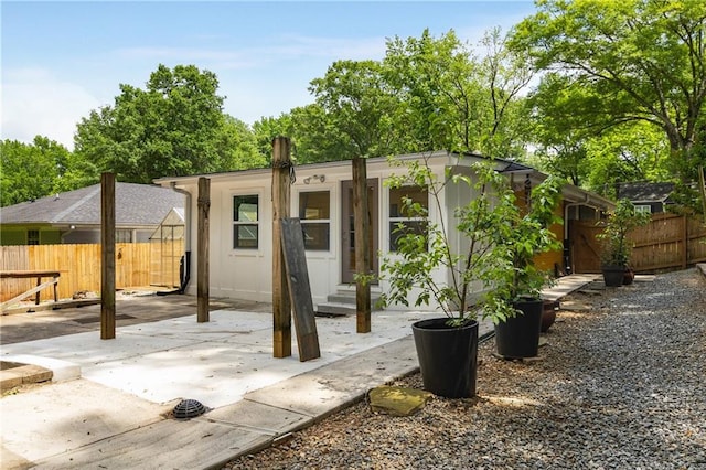 view of front of home with entry steps, fence, and a patio area