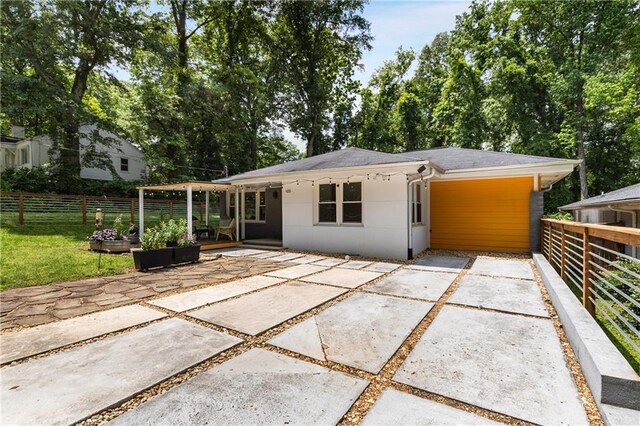 rear view of property featuring a patio area, fence, driveway, and stucco siding