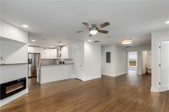 unfurnished living room with electric panel, ceiling fan, dark wood finished floors, recessed lighting, and a glass covered fireplace