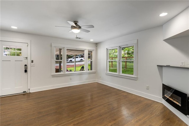unfurnished living room with dark wood finished floors, baseboards, ceiling fan, recessed lighting, and a glass covered fireplace