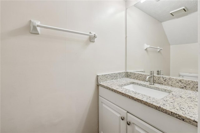 bathroom with a textured ceiling, toilet, and vanity