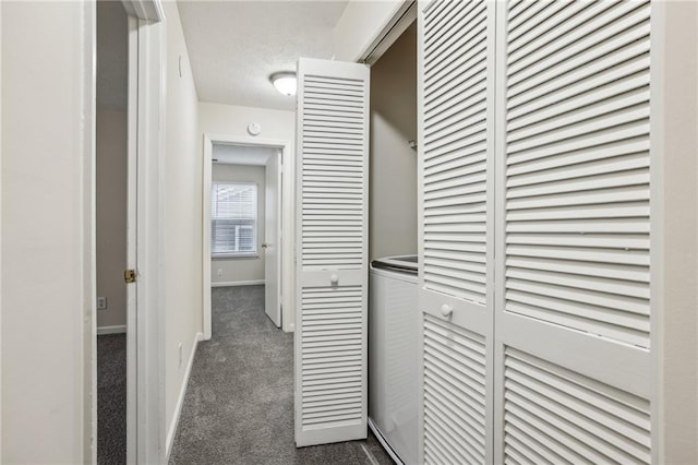 hallway featuring dark carpet and a textured ceiling