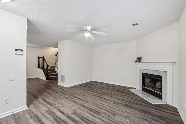 unfurnished living room featuring ceiling fan, a textured ceiling, dark hardwood / wood-style flooring, and a premium fireplace