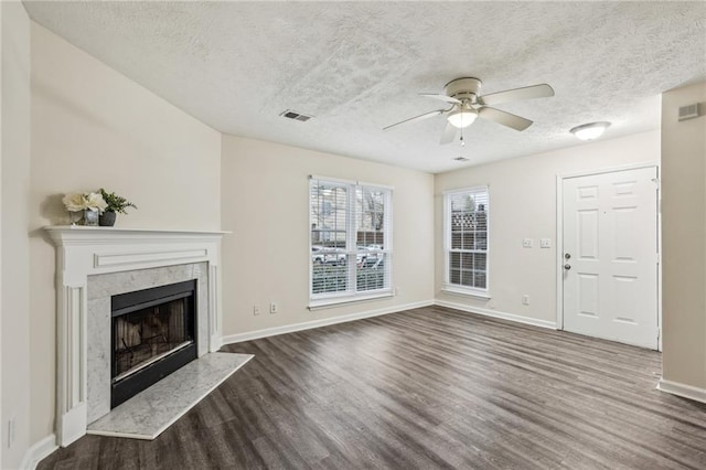 unfurnished living room with a premium fireplace, ceiling fan, dark hardwood / wood-style flooring, and a textured ceiling