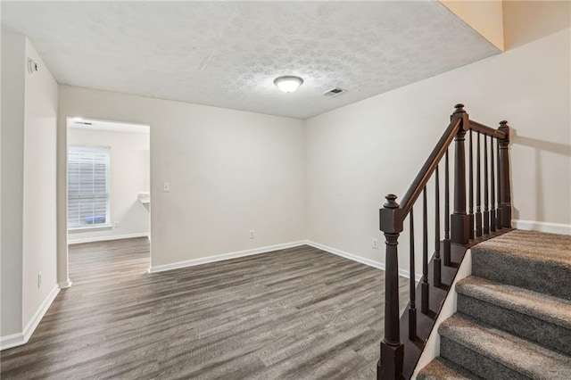 staircase featuring hardwood / wood-style flooring and a textured ceiling