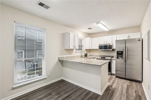 kitchen featuring sink, white cabinetry, appliances with stainless steel finishes, and kitchen peninsula