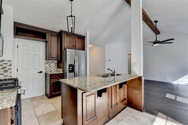 kitchen with appliances with stainless steel finishes, decorative light fixtures, lofted ceiling with beams, light stone counters, and kitchen peninsula