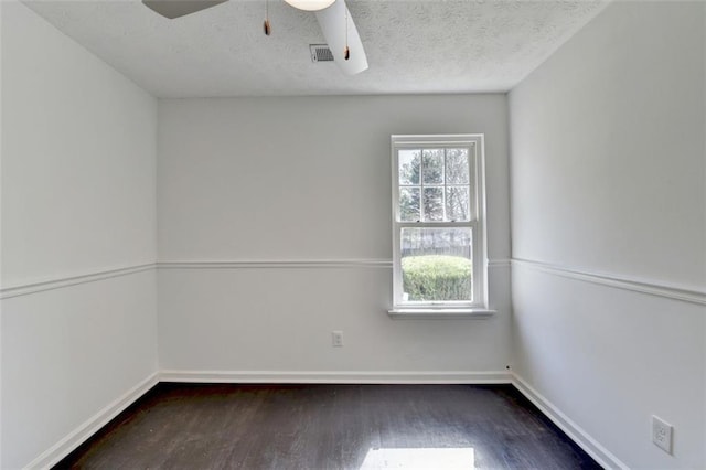 unfurnished room with a textured ceiling, dark wood-type flooring, and ceiling fan