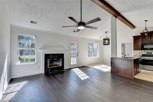 kitchen with dark hardwood / wood-style floors, tasteful backsplash, vaulted ceiling with beams, stainless steel gas range, and a textured ceiling