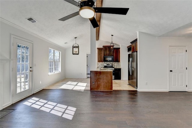 kitchen featuring pendant lighting, appliances with stainless steel finishes, backsplash, a kitchen island, and vaulted ceiling