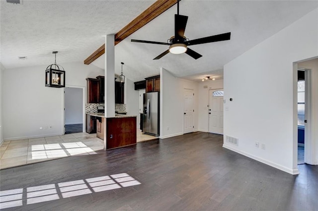 unfurnished living room featuring ceiling fan, a healthy amount of sunlight, light hardwood / wood-style floors, and lofted ceiling with beams