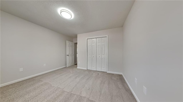 unfurnished bedroom featuring a closet, light carpet, and a textured ceiling