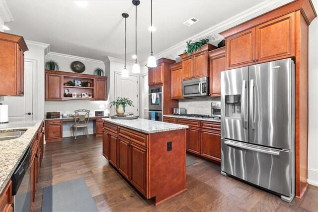 kitchen featuring light stone counters, a kitchen island, stainless steel appliances, and decorative light fixtures