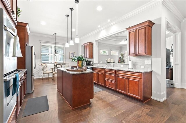 kitchen featuring a center island, sink, stainless steel appliances, dark hardwood / wood-style floors, and decorative light fixtures