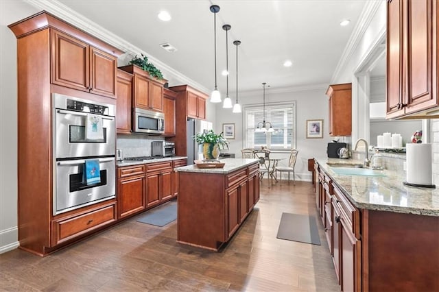 kitchen featuring decorative light fixtures, stainless steel appliances, ornamental molding, and sink