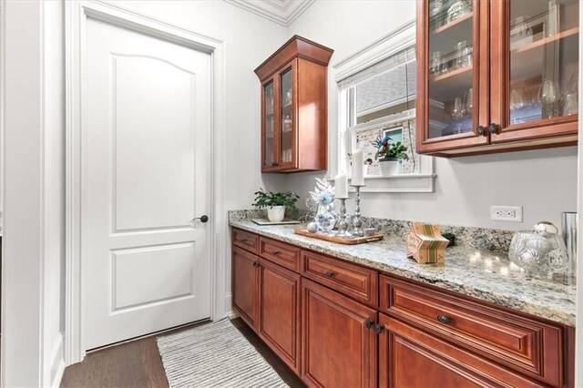 bar featuring dark hardwood / wood-style flooring, light stone countertops, and crown molding